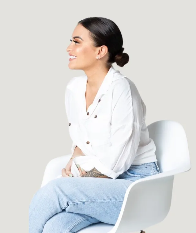 Erica Battista, smiling, seated in a white blouse.